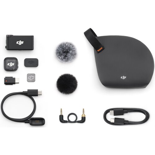Na zdjęciu znajduje się zestaw akcesoriów do systemu bezprzewodowego DJI Mic 3, w tym mikrofon, odbiornik, dwa futrzane osłony przeciwwietrzne, różne kable i adaptery oraz etui z logo DJI. Wszystkie elementy są rozłożone na białym tle, a logo DJI jest wid
