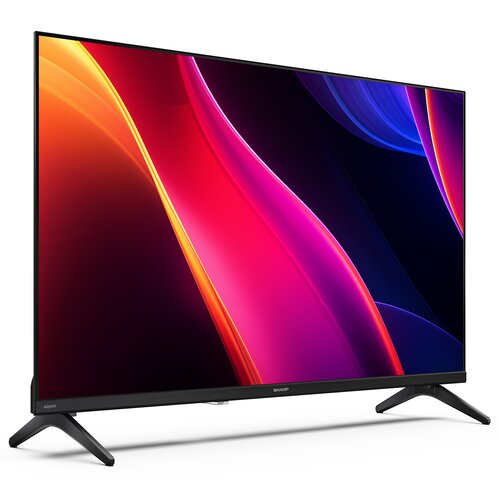 Telewizor z cienką ramką i dwoma nóżkami, wyświetlający kolorową grafikę z dominującymi odcieniami czerwieni, różu i niebieskiego. Na dolnej ramce widoczne są napisy: "AQUOS" i "SHARP".