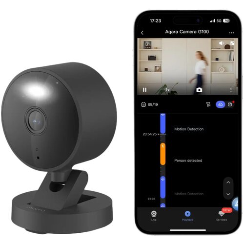 Czarna kamera o nowoczesnym designie stoi na podstawce, obok niej widoczny jest ekran smartfona z aplikacją "Aqara Camera G100", na którym widać interfejs z podglądem wideo i wykryciem ruchu. Na ekranie smartfona znajdują się napisy: "Motion Detection", "