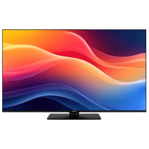 Na zdjęciu widoczny jest telewizor z cienką ramką, wyświetlający kolorowe, abstrakcyjne fale w odcieniach pomarańczowego, czerwonego i niebieskiego. Na dolnej ramce telewizora znajduje się logo "Panasonic".