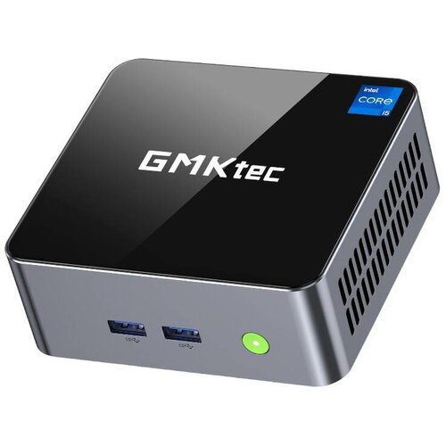 Na zdjęciu znajduje się kompaktowy komputer z logo "GMKtec" na górnej powierzchni obudowy. Na obudowie widoczny jest również napis "intel CORE i5", dwa porty USB oraz okrągły przycisk z zielonym podświetleniem.