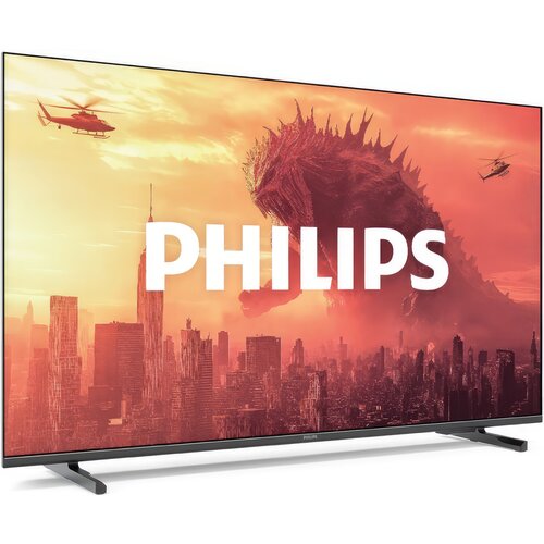 Telewizor z dużym ekranem wyświetla obraz przedstawiający miasto z wieżowcami, nad którym unosi się duża postać przypominająca potwora oraz dwa helikoptery na tle pomarańczowego nieba. Na środku ekranu widnieje duży, biały napis "PHILIPS".