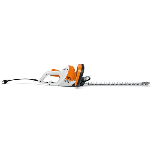 Na zdjęciu widoczne są elektryczne nożyce do żywopłotu w kolorach białym, pomarańczowym i czarnym. Na obudowie znajduje się napis "STIHL HSE 52".