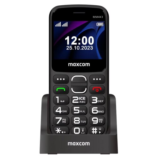 Telefon komórkowy z dużymi przyciskami, wyświetlający godzinę 12:00 i datę 25.10.2023 na ekranie, umieszczony w stacji dokującej. Na obudowie widoczne jest logo "maxcom" oraz model "MM443".