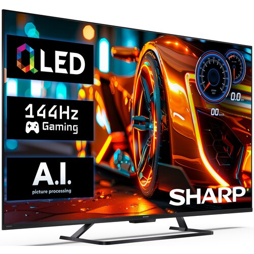 Na zdjęciu widoczny jest telewizor z kolorowym obrazem przedstawiającym futurystyczny samochód, z wyświetlonymi napisami: "QLED", "144Hz Gaming", "A.I. picture processing" oraz logo "SHARP". Telewizor ma nowoczesny design z cienką ramką i stoi na metalowe
