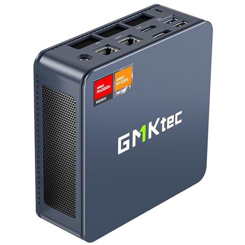 Kompaktowy komputer w ciemnoszarej obudowie z widocznym logo "GMKtec" na boku. Na górnej powierzchni znajdują się porty oraz naklejki z napisami "AMD Radeon Graphics" i "AMD Ryzen 7 7000 Series".