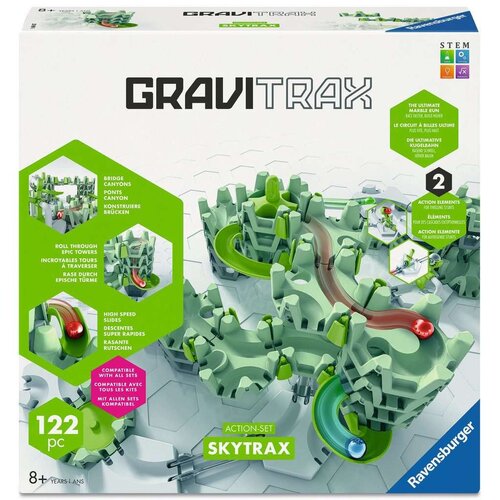 Opakowanie gry logicznej "Gravitrax Zestaw startowy Skytrax" marki Ravensburger, zawiera ilustrację toru kulkowego z elementami w kolorach zielonym i szarym oraz czerwonymi i niebieskimi kulkami. Na opakowaniu widnieją napisy: "GRAVITRAX", "122 pc", "ACTI