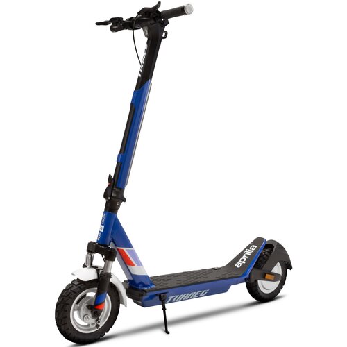Na zdjęciu znajduje się granatowa hulajnoga elektryczna z amortyzacją i dużymi kołami, z widocznymi napisami "aprilia" na podeście i "TUAREG" na ramie. Hulajnoga ma czarne i białe elementy oraz kolorowe akcenty na przednim widelcu.