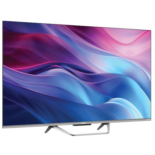 Telewizor z cienką ramką wyświetla abstrakcyjny obraz w odcieniach różu, fioletu i niebieskiego. Na dolnej ramce widoczne jest logo "Haier".