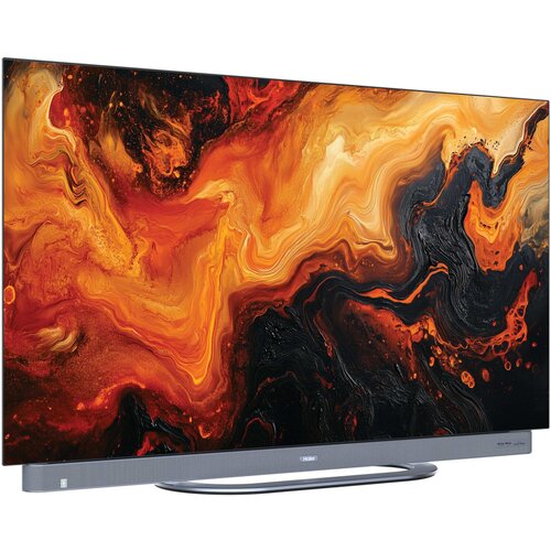 Telewizor z wyświetlaczem prezentującym abstrakcyjny wzór w odcieniach pomarańczowego, czarnego i żółtego. Na dolnej ramce widoczne jest logo "Haier".