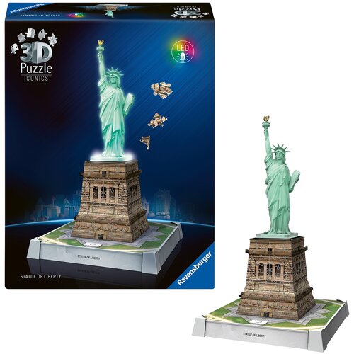Pudełko przedstawia model 3D Statuy Wolności z efektem świetlnym LED, z widocznymi elementami puzzli unoszącymi się w powietrzu. Na podstawie modelu znajduje się napis "STATUE OF LIBERTY", a na pudełku widnieje logo "Ravensburger".