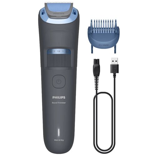 Na zdjęciu znajduje się ciemnoszary trymer z niebieskimi elementami, obok którego leży niebieska nasadka z oznaczeniem "0.5-10MM" oraz czarny kabel USB. Na trymerze widoczny jest napis "PHILIPS Beard Trimmer Wet & Dry" oraz pokrętło z oznaczeniami długośc