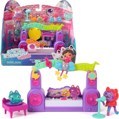 Zestaw figurek przedstawia kolorową scenę z instrumentami muzycznymi i postaciami z bajki, w tym mikrofonem i klawiaturą. Na opakowaniu widnieje napis: "Gabby's Dollhouse The Movie" oraz "Paw-some Party Story", a także ostrzeżenie: "WARNING: CHOKING HAZAR