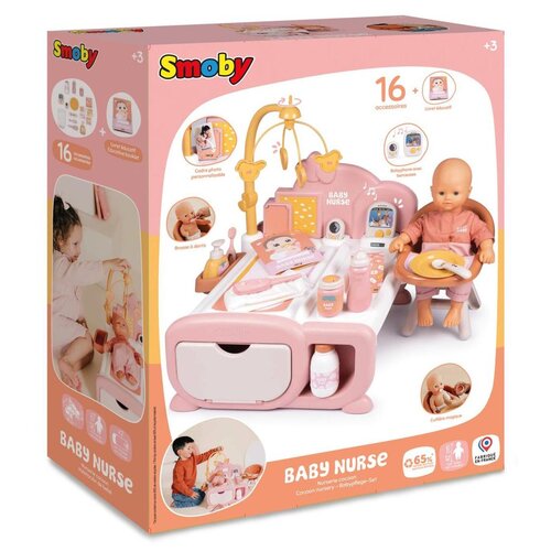 Opakowanie produktu "Kącik opiekunki SMOBY Baby Nurse 7600220393" przedstawia zestaw do zabawy z lalką, łóżeczkiem i akcesoriami w kolorze różowym. Na opakowaniu widnieje logo "Smoby", napis "16+ accessories" oraz zdjęcia dzieci bawiących się zestawem.