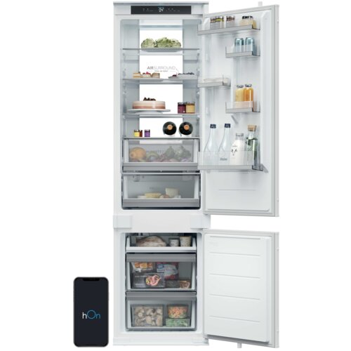 Na zdjęciu widoczna jest otwarta lodówka z różnymi produktami spożywczymi na półkach, w tym warzywami, napojami i słoikami. Na drzwiach lodówki znajduje się logo "hOn", a na wewnętrznej ściance napis "AIR SURROUND Total No Frost".
