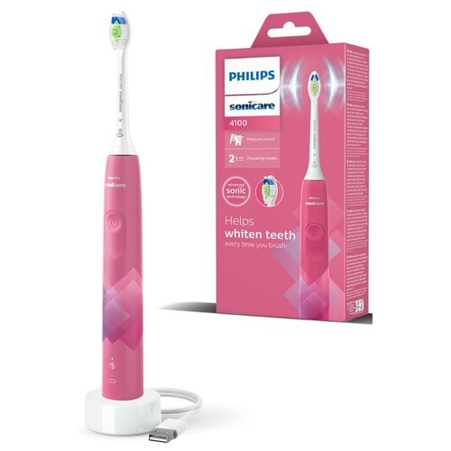 Różowa szczoteczka soniczna PHILIPS Sonicare 4100 HX3689 41 stoi na białej ładowarce z kablem USB, obok znajduje się różowe opakowanie z napisem "PHILIPS sonicare 4100" oraz "Helps whiten teeth every time you brush". Na opakowaniu widoczne są również ikon