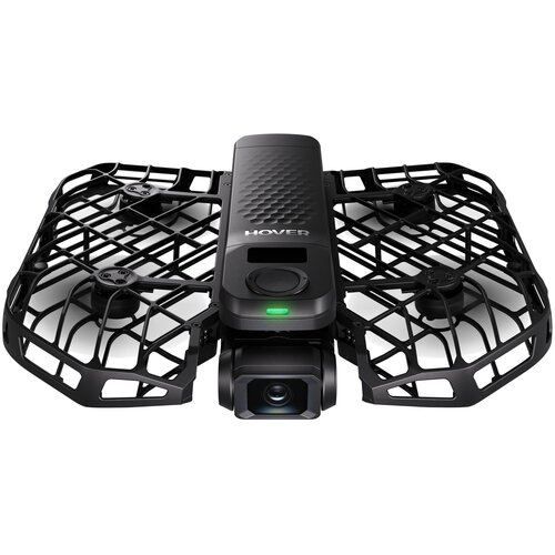 Na zdjęciu widoczny jest dron z czarną, kratkowaną obudową ochronną i kamerą z przodu. Na górnej części drona znajduje się napis "HOVER" oraz zielona dioda.