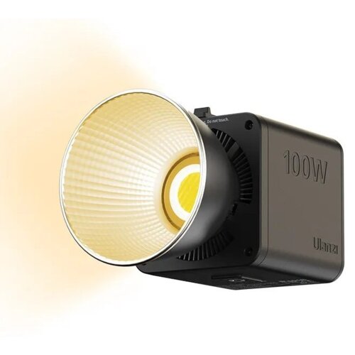 Kwadratowa lampa LED z widocznym reflektorem emituje ciepłe światło, na obudowie widnieje napis "100W" oraz "Ulanzi". Na górze obudowy znajduje się napis "Do not touch".