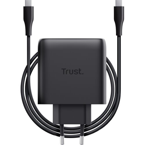 Czarny zasilacz do laptopa z logo "Trust." na środku, z dołączonym kablem USB-C owiniętym wokół urządzenia. Produkt ma kompaktowy, prostokątny kształt z widocznymi dwoma bolcami wtyczki.