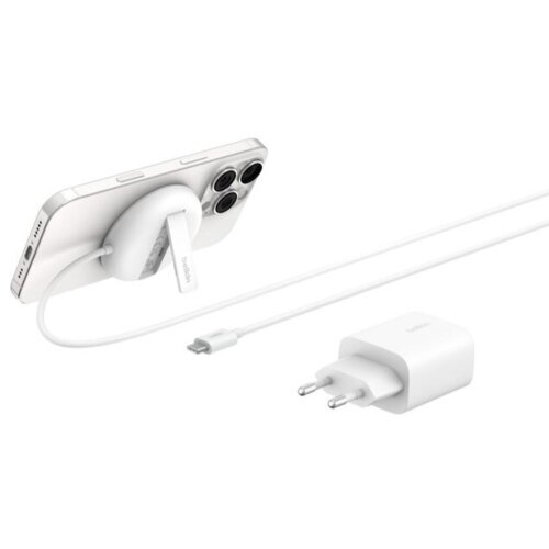 Na zdjęciu znajduje się biała ładowarka indukcyjna z napisem "belkin" podtrzymująca smartfon oraz biały zasilacz z dwoma bolcami i napisem "belkin". Kabel łączy ładowarkę z zasilaczem.
