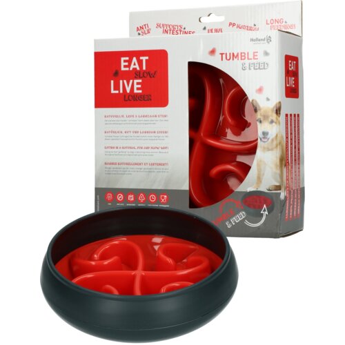 Czarno-czerwona miska dla zwierząt z labiryntowym wzorem, obok opakowanie z napisem "EAT SLOW LIVE LONGER" oraz "TUMBLE & FEED". Na opakowaniu znajdują się również piktogramy i teksty w kilku językach, a także zdjęcie psa.