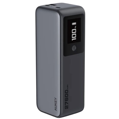 Szary powerbank z wyświetlaczem pokazującym "100%" oraz napisem "AUKEY" i "27600 mAh" na obudowie. Urządzenie ma zaokrąglone krawędzie i porty na górze.