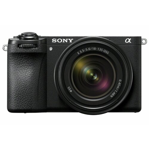 Czarny aparat bezlusterkowy z widocznym logo "SONY" oraz symbolem "α" na korpusie, wyposażony w obiektyw z oznaczeniami "E 3.5-5.6/18-135 OSS" i "Ø 0.45m/1.48ft". Aparat posiada teksturowany uchwyt i duży obiektyw z widocznymi refleksami świetlnymi na soc