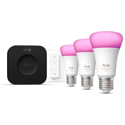 Na zdjęciu znajduje się zestaw startowy Philips Hue, składający się z trzech żarówek z różowymi kloszami, mostka oraz regulatora. Na żarówkach widoczny jest napis "hue white and color 1100", a na mostku i regulatorze logo "hue".