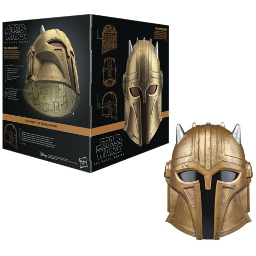 Na zdjęciu znajduje się złoty hełm z serii Star Wars The Black Series, obok którego widoczny jest czarny karton z grafiką hełmu i napisami: "STAR WARS: THE MANDALORIAN", "THE ARMORER", "STAR WARS THE BLACK SERIES". Na opakowaniu znajdują się również schem