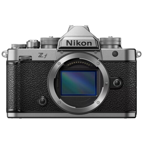 Aparat bezlusterkowy z widocznym logo "Nikon" na górze, z oznaczeniem modelu "Z f" po lewej stronie. Korpus aparatu ma srebrne i czarne elementy, z widocznym miejscem na obiektyw.