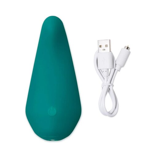 Zielony masażer o gładkiej powierzchni obok białego kabla USB z końcówką micro USB. Na masażerze widoczny jest delikatny symbol włącznika.