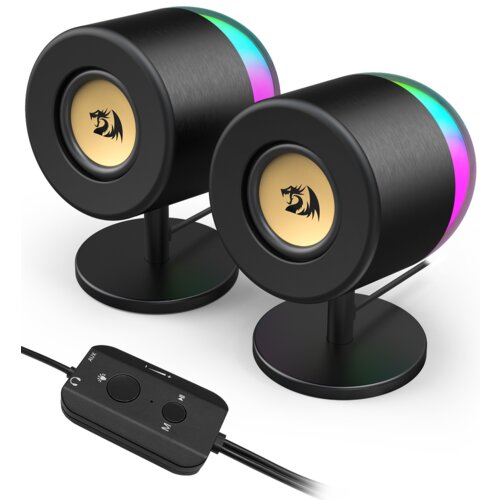 Dwa cylindryczne głośniki z czarnym wykończeniem i kolorowym podświetleniem RGB, umieszczone na okrągłych podstawkach, z widocznym logo smoka na złotym tle. Przed głośnikami znajduje się przewodowy pilot z przyciskami do regulacji głośności, jasności i pr