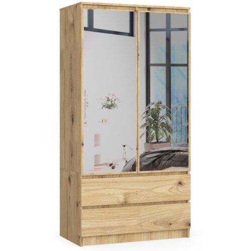 Drewniana szafa w kolorze Dąb Artisan z dwoma drzwiami, z których jedno jest lustrem, oraz dwiema szufladami na dole. W tle odbija się wnętrze pokoju z rośliną i dużym oknem.