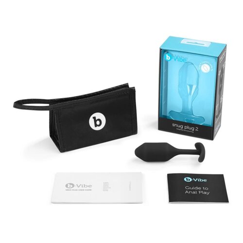 Na zdjęciu znajduje się czarny korek analny obok czarnej torby z logo "b" oraz dwóch broszur: jedna z napisem "b-Vibe Snug Plug User Guide", a druga "b-Vibe Guide to Anal Play". W tle widoczne jest opakowanie z przezroczystym frontem i napisem "snug plug 2".