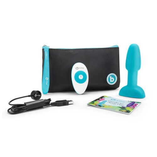 Na zdjęciu znajduje się zestaw produktów, w tym turkusowy korek analny, czarno-turkusowa torba z logo "b vibe", biało-turkusowy pilot z logo "b vibe", kabel USB oraz kolorowa broszura z napisem "b vibe guide to Anal Play".