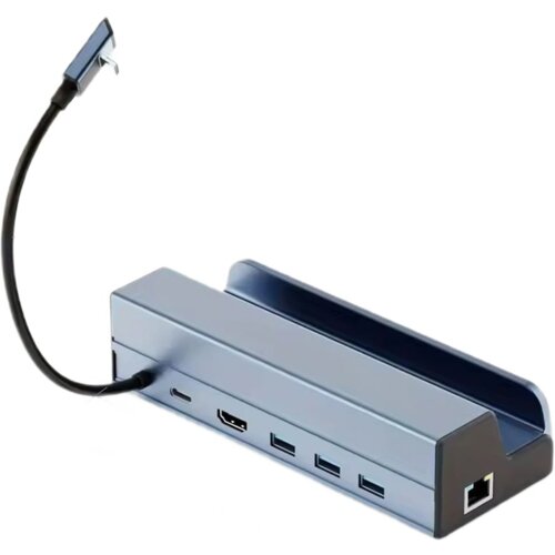 Srebrna stacja dokująca z kilkoma portami, w tym USB Typu C, HDMI, trzema portami USB oraz portem Ethernet, posiada krótki kabel z wtyczką USB Typu C. Produkt ma prostokątny kształt z miejscem na urządzenie na górze.