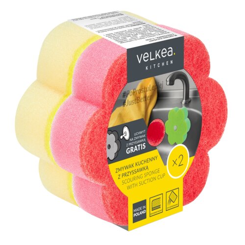 Opakowanie zawiera dwa zmywaki kuchenne w kształcie kwiatka, w kolorach żółtym i różowym, z etykietą z napisem "velkea. KITCHEN" oraz hasłami "#PoProstuLepiej #JustBetter". Na etykiecie znajduje się informacja o gratisowym uchwycie z przyssawką oraz napis "ZMYWAK KUCHENNY Z PRZYSSAWKĄ GRATIS", a także oznaczenie "MADE IN POLAND".