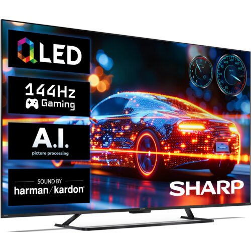 Telewizor z wyświetlaczem prezentującym kolorowy, futurystyczny samochód z efektami świetlnymi, obok którego znajdują się napisy: "QLED", "144Hz Gaming", "A.I. picture processing", "SOUND BY harman/kardon" oraz logo "SHARP". W tle widoczne są rozmyte światła, a w prawym górnym rogu znajdują się dwa wskaźniki przypominające zegary.