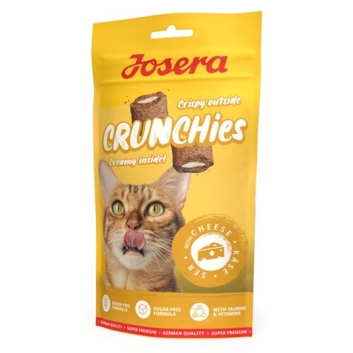 Żółte opakowanie przysmaku dla kota z napisem "Josera Crunchies" oraz wizerunkiem kota z wywieszonym językiem. Na opakowaniu znajdują się również informacje: "Crispy outside, Creamy inside!", "With Cheese - Käse - Ser", "Grain Free Formula", "Sugar Free Formula", "With Taurine & Vitamins", oraz "German Quality - Super Premium".