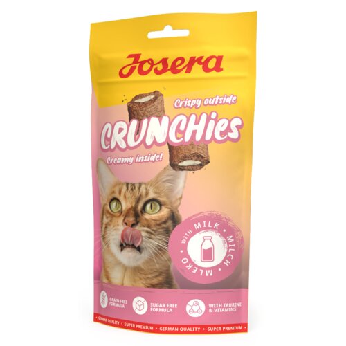 Opakowanie przysmaku dla kota JOSERA Crunchies With Milk 60 g przedstawia wizerunek kota z wywieszonym językiem oraz grafikę przysmaku z napisem "Crispy outside, Creamy inside!". Na dole opakowania znajdują się ikony z napisami: "Grain Free Formula", "Sugar Free Formula", "With Taurine & Vitamins", a także okrągła grafika z napisem "With Milk".
