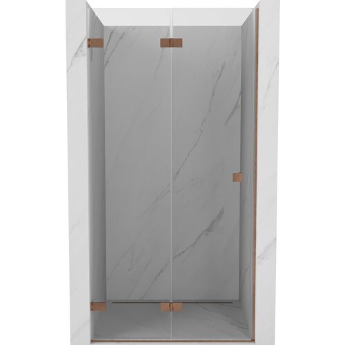 Drzwi prysznicowe składane o transparentnej powierzchni, z miedzianymi, szczotkowanymi elementami mocującymi, zamontowane w marmurowej wnęce. Produkt ma minimalistyczny design z widocznymi delikatnymi żyłkami na powierzchni.