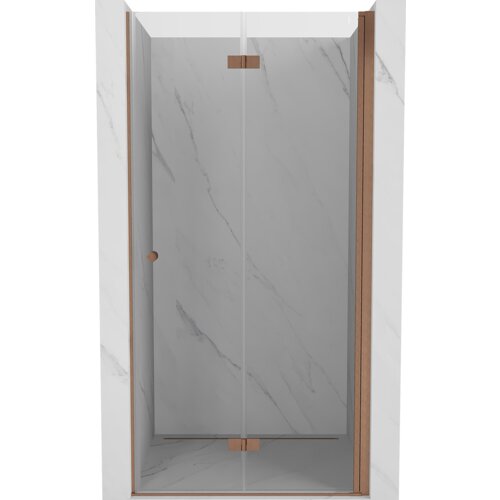 Drzwi prysznicowe składane wykonane z przezroczystego szkła, z miedzianymi, szczotkowanymi elementami wykończenia, zamontowane w marmurowej wnęce. Produkt ma minimalistyczny design z prostymi liniami i eleganckim wykończeniem.