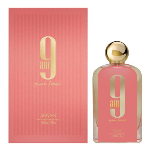 Na zdjęciu widoczna jest różowa butelka perfum z dużym złotym napisem "9 am pour femme" oraz złotym korkiem, obok znajduje się różowe opakowanie z tym samym napisem. Na dole opakowania widnieje napis "AFNAN eau de parfum vaporisateur e100ml 3.4Fl.oz".