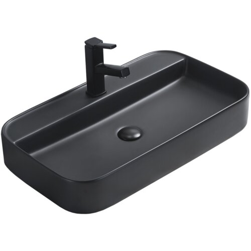 Czarna matowa umywalka nablatowa o prostokątnym kształcie z zaokrąglonymi rogami, wyposażona w czarną baterię. Na powierzchni umywalki widoczny jest odpływ w tym samym kolorze.