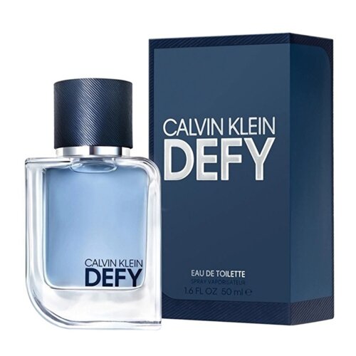 Na zdjęciu widoczna jest butelka perfum z niebieskim płynem oraz ciemnoniebieskie opakowanie z napisem "CALVIN KLEIN DEFY" i informacją "EAU DE TOILETTE SPRAY VAPORISATEUR 1.6 FL OZ 50 ml".