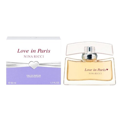 Na zdjęciu widoczna jest butelka perfum oraz pudełko z napisem "Love in Paris" i "Nina Ricci". Pudełko ma fioletowy dół z białym sercem i napisami "EAU DE PARFUM VAPORISATEUR SPRAY" oraz "e 50 ml 1.7 FL.OZ.".