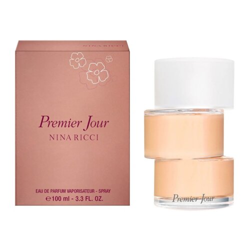 Pudełko w kolorze różowym z białymi kwiatami i napisami: "Premier Jour NINA RICCI" oraz "EAU DE PARFUM VAPORISATEUR - SPRAY e 100 ml - 3.3 FL. OZ." Obok znajduje się flakon perfum o cylindrycznym kształcie z białą nakrętką i napisem "Premier Jour".