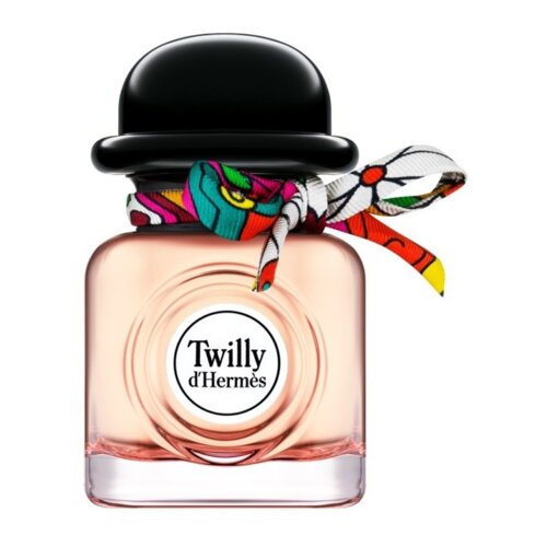 Kwadratowy flakon perfum z różowego szkła, z czarnym, okrągłym korkiem przypominającym kapelusz, ozdobiony kolorową wstążką. Na froncie flakonu znajduje się okrągła etykieta z napisem "Twilly d'Hermès".