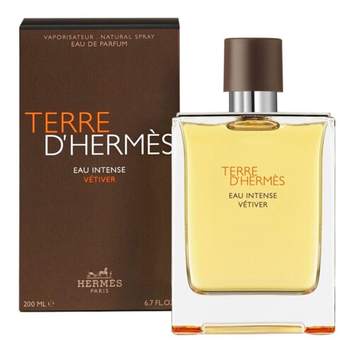 Na zdjęciu widoczna jest butelka perfum z brązowym korkiem oraz pudełko w ciemnym kolorze z napisem "TERRE D'HERMÈS EAU INTENSE VÉTIVER". Na dole pudełka znajduje się logo "HERMÈS PARIS" oraz oznaczenie pojemności "200 ML 6.7 FL.OZ".