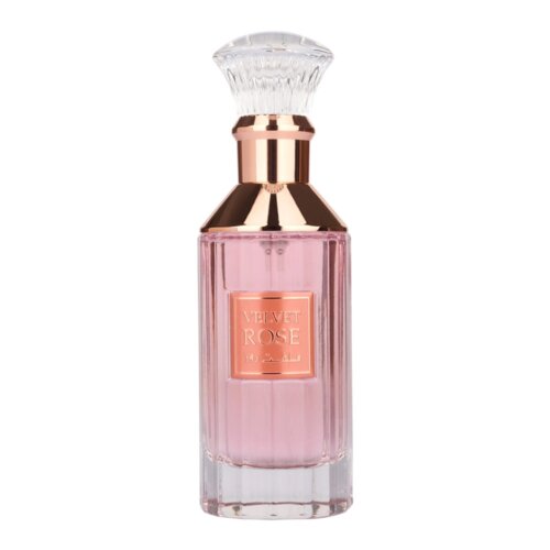 Butelka perfum o różowym odcieniu z przezroczystym, ozdobnym korkiem i złotym akcentem na szyjce, na której widnieje etykieta z napisem "VELVET ROSE".